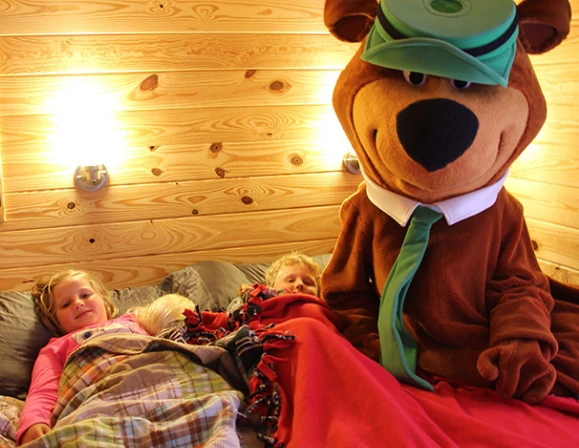 Yogi Bear tucking in two kids